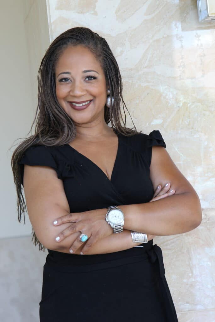 Donna Bohana Headshot Donna Bohana, Coastal California luxury real estate expert, smiling with arms crossed in professional headshot wearing a black dress against a light background